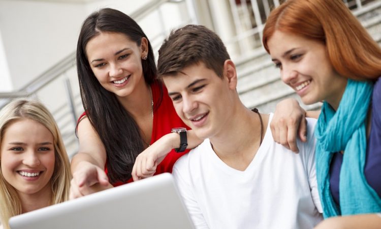 Group of university students using laptop outdoors